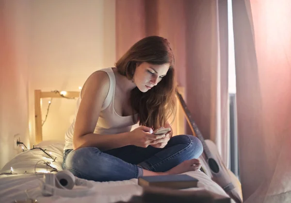 Κορίτσι Ένα Smartphone Στο Κρεβάτι Της — Φωτογραφία Αρχείου