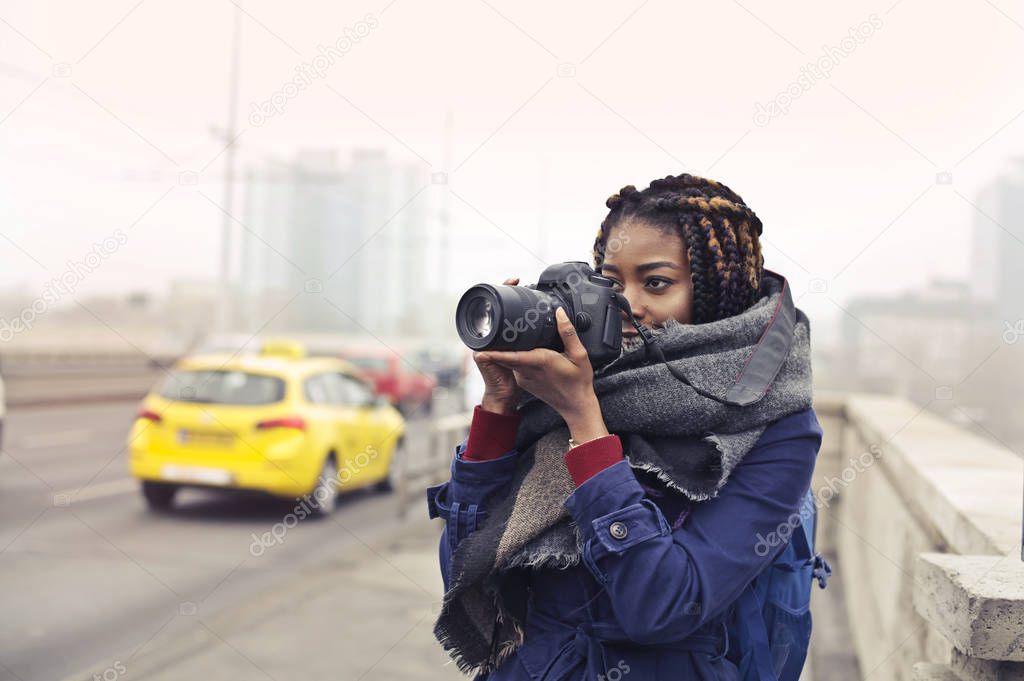 Girl in a city street making photos 