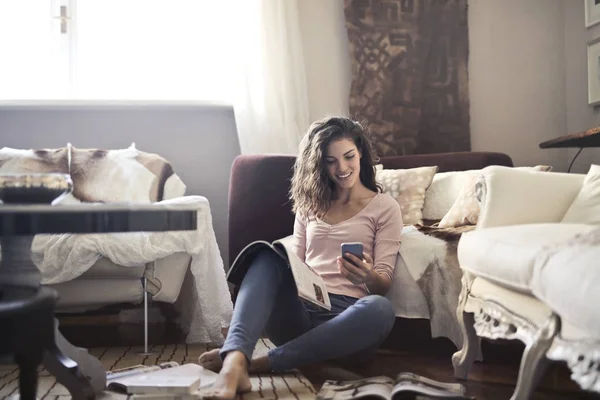 Menina Uma Sala Estar Lendo Uma Revista Usando Smartphone — Fotografia de Stock