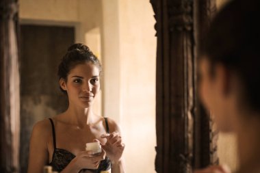 Kız bir yüz kremi kullanarak bir ayna önünde