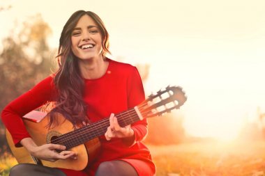 Bir gitar çalmak Kırmızı elbiseli genç kadın