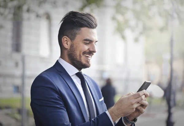 Empresário Sorrindo Enquanto Olha Para Seu Telefone — Fotografia de Stock