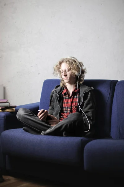 Αγόρι Ακούτε Μουσική Ακουστικά Που Κάθεται Στον Καναπέ Του — Φωτογραφία Αρχείου