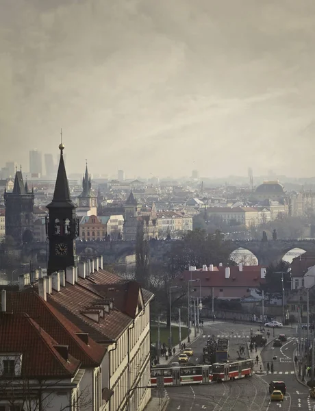 Cityscape of Prague with antique buildings, a bridge and some means of transport