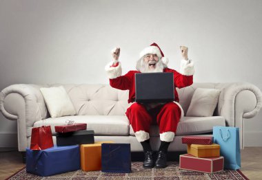Noel Baba GIF'ler tarafından çevrili bir koltuk exulting dizlerinin üzerinde bir dizüstü bilgisayar ile oturup...