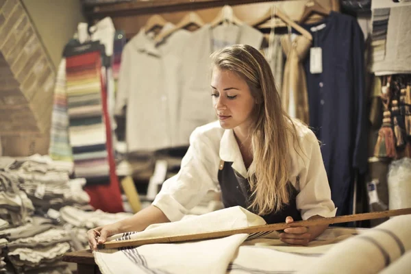 Young blond artisan at work in her laboratory with some fabrics