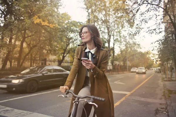 エレガントな女性の通り都市の自転車に乗っている間彼女の電話を使用して — ストック写真