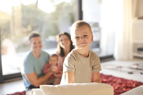 バック グラウンドで彼の家族が付いているソファーに白人の子供の肖像画 — ストック写真