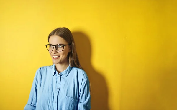 Gülümseyen Beyaz Genç Kadın Portresi Sarı Bir Duvarın Önünde Gözlük — Stok fotoğraf
