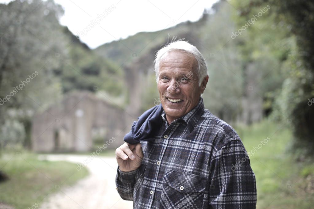 Portrait of an aged caucasian man with a plaid shirt in a mountain area