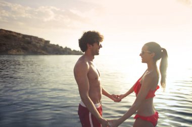 Kumsalda el ele tutuşan bir çift.