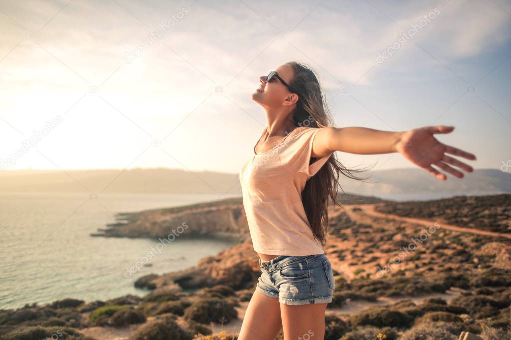 Girl with open arms near the sea