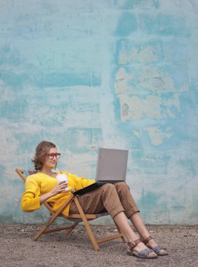 Genç kadın bir dizüstü bilgisayar kullanarak bir şezlong üzerinde