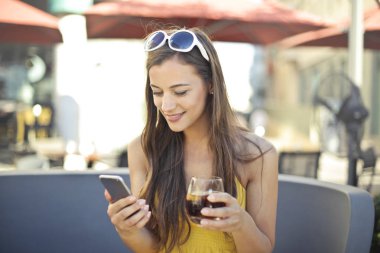 Açık bir barda bir akıllı telefon kullanan kız