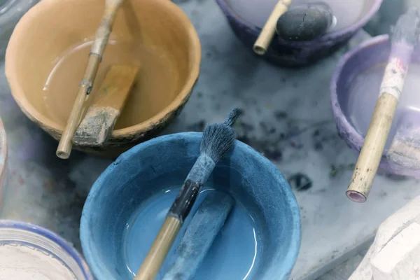 Paint in bowls with simple brushes in an artist studio.