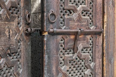 Yaşlı Faslı, ahşap kapı koruması. Açık kapı, hoş geldin ve misafirperverlik kavramı. Kuran Okulu, Madrasa Bou Inania, Fas, Fas