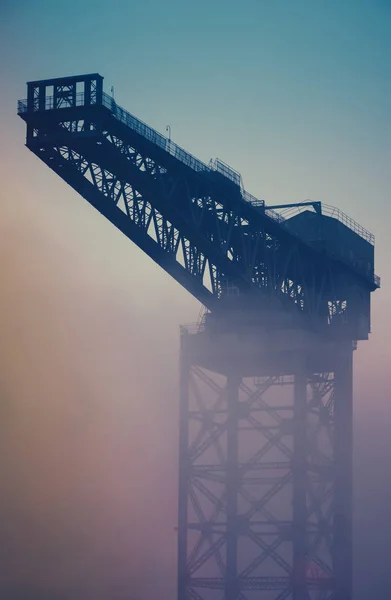 Grúa industrial al amanecer en la niebla — Foto de Stock