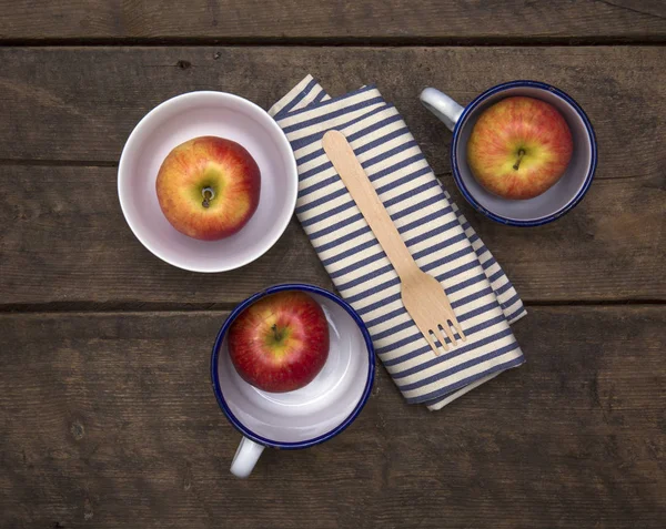 Äpplen i skålar med gaffel och servetter på ett rustikt träbord — Stockfoto