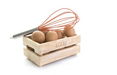 Yumurta beyaz bir arka planda turuncu yumurta çırpma teli ile mezarda