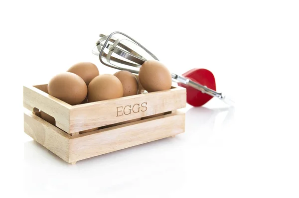 Œufs dans une boîte en bois avec un vieux fouet d'œufs rouges sur fond blanc — Photo