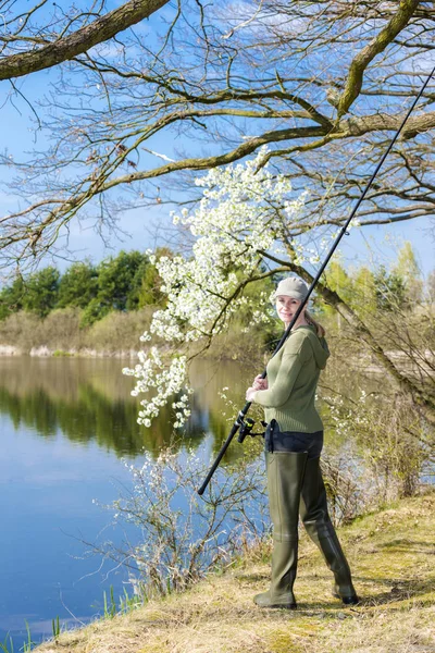 Mulher pesca na lagoa na primavera — Fotografia de Stock