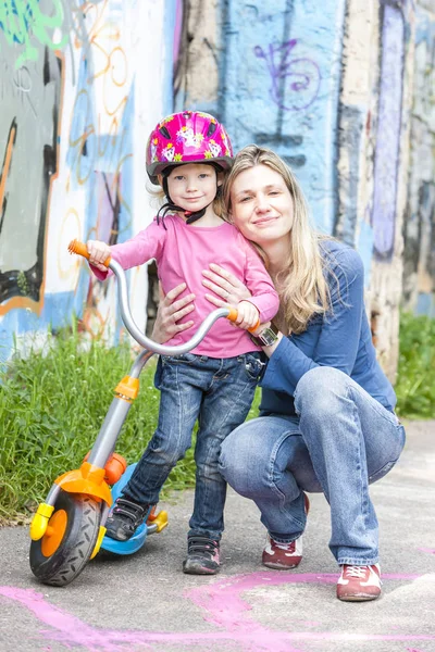 Menina com uma scooter e sua mãe — Fotografia de Stock