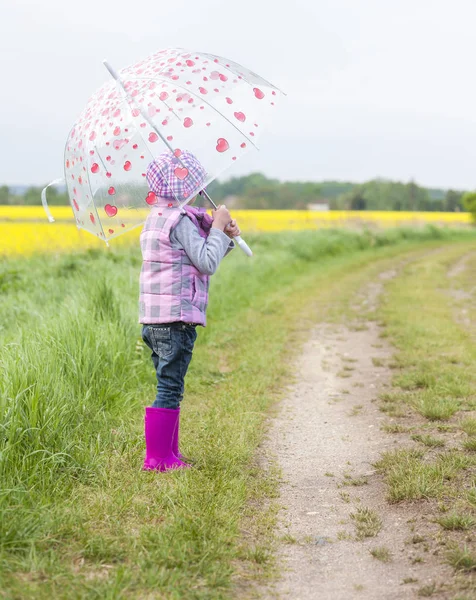 Niña con paraguas en la naturaleza de primavera — Foto de Stock