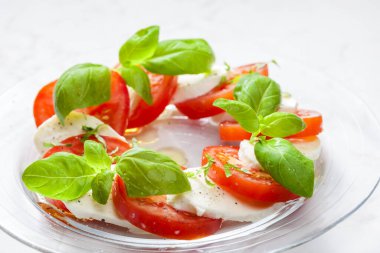 Olgun domatesli lezzetli caprese salatası ve taze fesleğen yapraklı mozzarella peyniri. İtalyan yemeği.