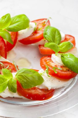 Olgun domatesli lezzetli caprese salatası ve taze fesleğen yapraklı mozzarella peyniri. İtalyan yemeği.