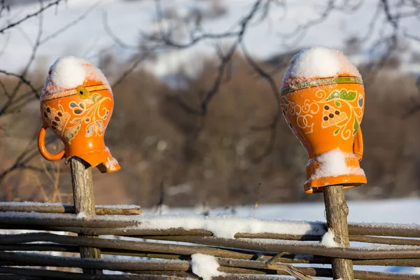 Ukrainian clay jugs on fence in winter — Stock Photo, Image