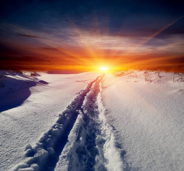 Gün batımı arka plan üzerinde kar üzerinde iz — Stok fotoğraf