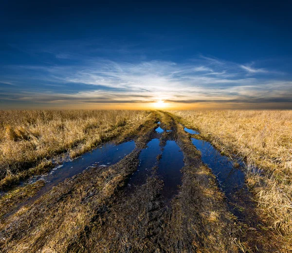 Pôr do sol sobre estrada de terra — Fotografia de Stock