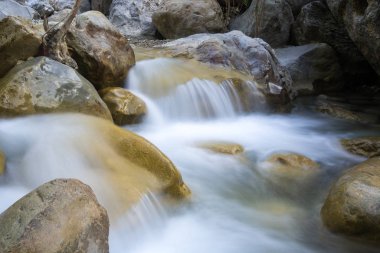 Dağ nehri üzerinde şelalesi olan bir manzara. Uzun bir sergi fotoğrafı