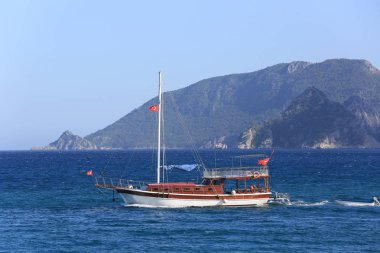Deniz üzerinde Türk bayrakları ve dağ pelerini olan bir tekne.