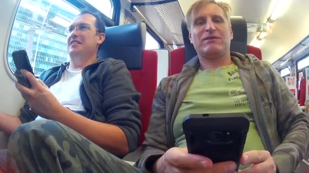 Två medelålders män ridande på ett tåg och talar — Stockvideo