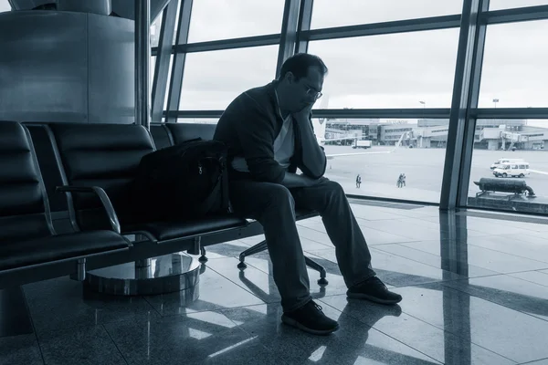 Smutny człowiek czeka na opóźniony lot — Zdjęcie stockowe
