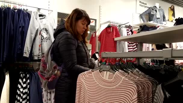 Young woman chooses clothes — Stock Video