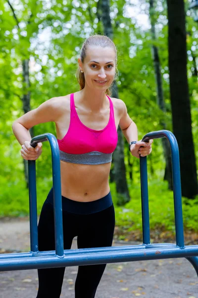 Jovem mulher magra fazendo treino em um campo de treinamento — Fotografia de Stock