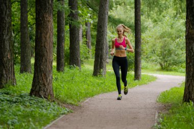 Genç bir kadın parkta koşuyor.