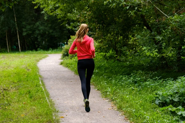 Genç bir kadın parkta koşuyor. — Stok fotoğraf