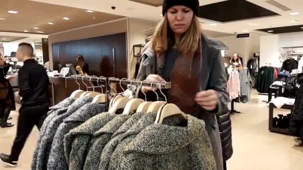 Mujer joven elige ropa — Vídeo de stock