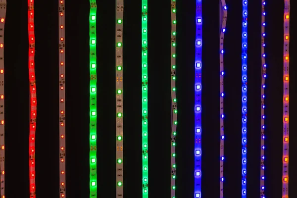 Leuchtende LED-Streifen in verschiedenen Farben auf Schwarz — Stockfoto