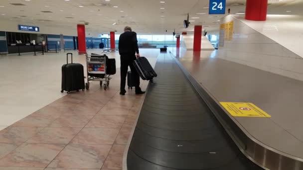 Trabajador del aeropuerto recoge el equipaje perdido del transportador — Vídeos de Stock
