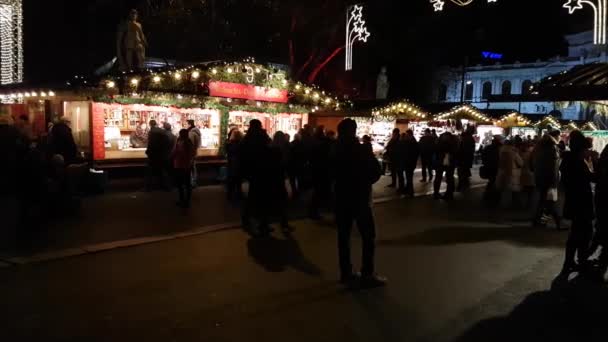 La gente visita el mercado de Navidad cerca del ayuntamiento por la noche — Vídeos de Stock