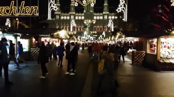 La gente visita el mercado de Navidad cerca del ayuntamiento por la noche — Vídeo de stock