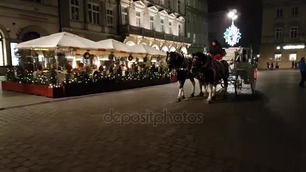 Turistas viajan en un carruaje alrededor del mercado de Navidad en la plaza principal en la ciudad vieja — Vídeo de stock