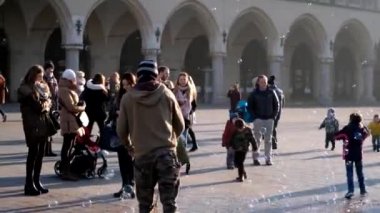 Üfleme kabarcıklar, mutlu turistler ve onlarla oynamak çocuk genç adam