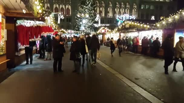 Люди посещают рождественский рынок возле ратуши вечером — стоковое видео
