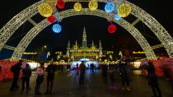 Orang-orang mengunjungi pasar Natal dekat balai kota di malam hari — Stok Video