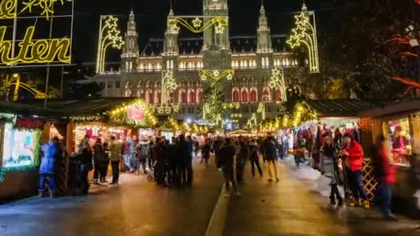 As pessoas visitam o mercado de Natal perto da prefeitura à noite — Vídeo de Stock